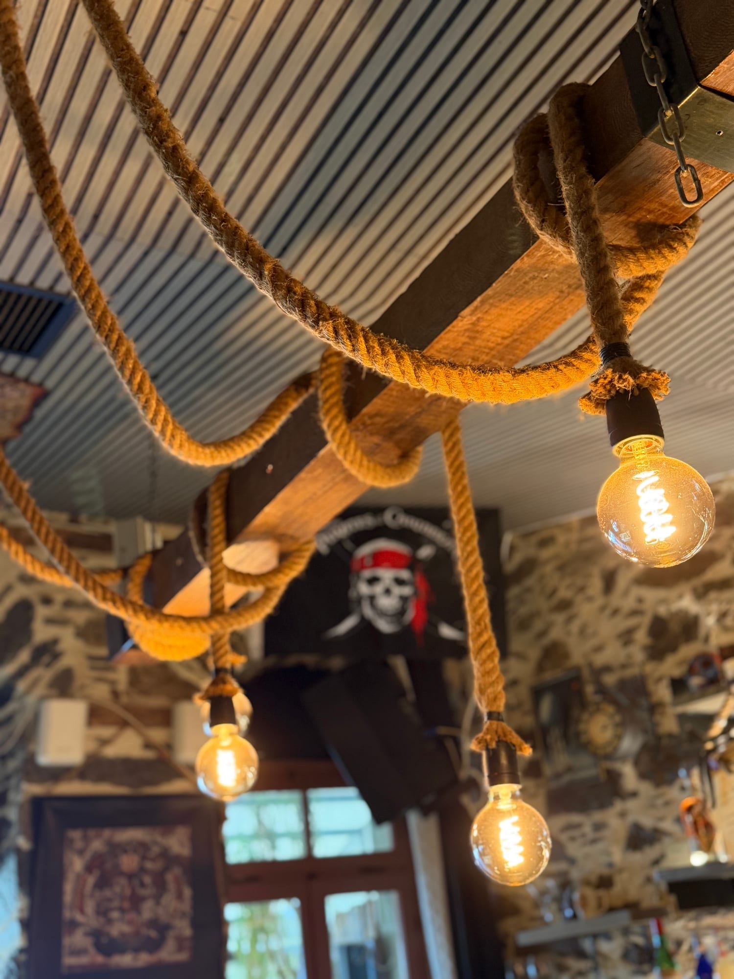 Warm Edison bulb lights strung in front of a Jolly Roger flag